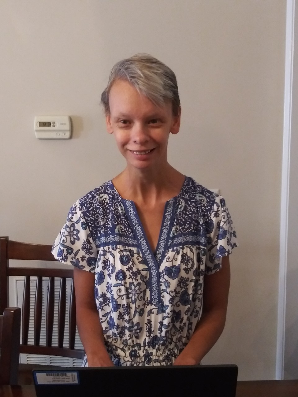Clancey’s headshot; she is a young white woman with blonde hair, a sweet smile, and a disability called William’s syndrome; she is wearing a blue patterned dress