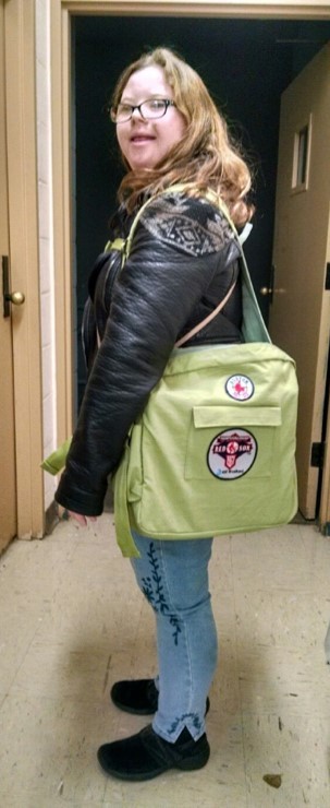 Olivia shows off her customized backpack, which keeps pressure off her back A young white woman with Down syndrome, long brown curly hair, a leather jacker and glasses is shown in two poses, one from the side and one from the back, with her new custom backpack that distributes weight on the sides of her body instead of her back.