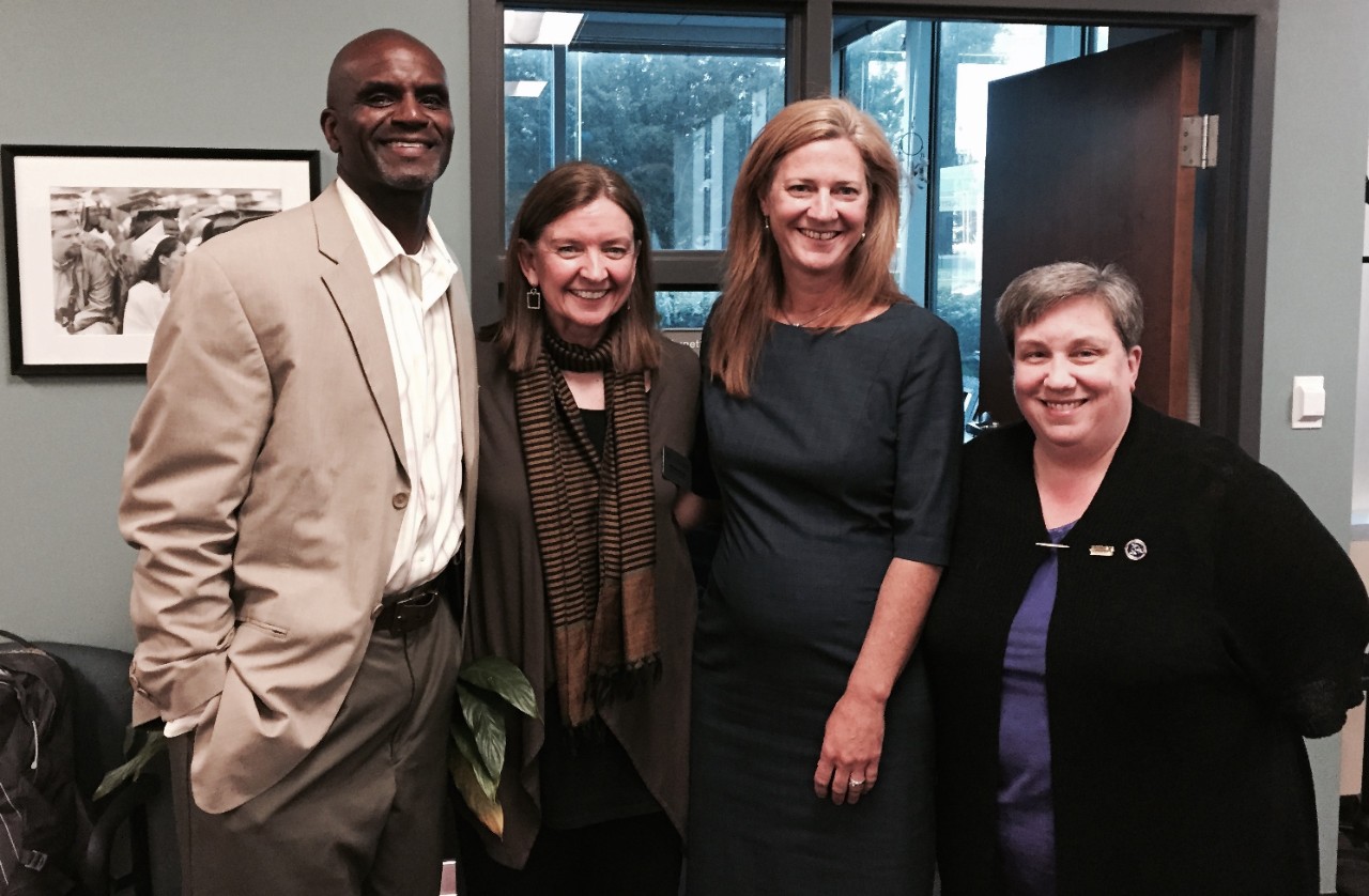 2015 CDD Aaron Bishop and Jennifer Johnson visit - Sept. 2015 Wanda stands between a Black man in a white shirt, light suit jacket and dress pants on the left and white woman who is wearing a dark dress with ¾ sleeves and has long, straight, light colored hair. Alicia Cone is on the far right – a white woman with short, light hair and wearing a black sweater over a blue top