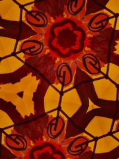 A drawing with black, orange, dark red and bright red markers of a pattern of flowers outlined by hexagons.