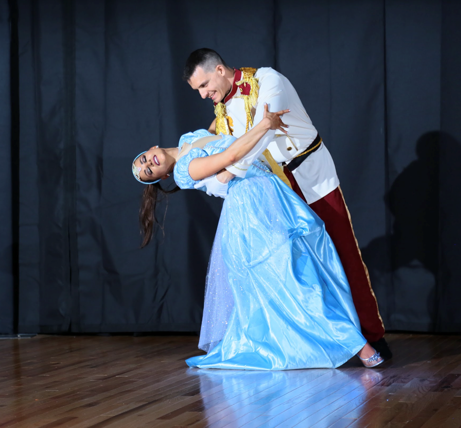 Brooke Mortimer and Ben Rubbelke perform together a woman dressed in a blue dress like Disney’s “Cinderella” and a man dipping her back in a dance move, dressed as Prince Charming from Cinderella.