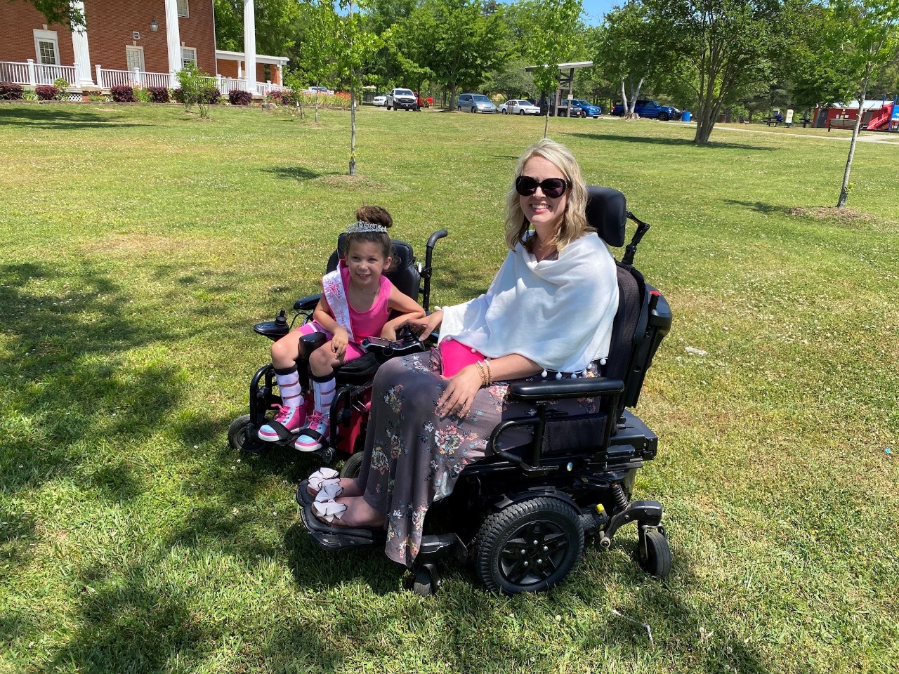 Little Miss Wheelchair Tennessee Anora Martin and Bliss Welch Anora is a young girl of maybe 4-6 years old seated in a wheelchair with a tiara wearing pink and smiling for the photo next to Bliss outdoors; both are in power wheelchairs