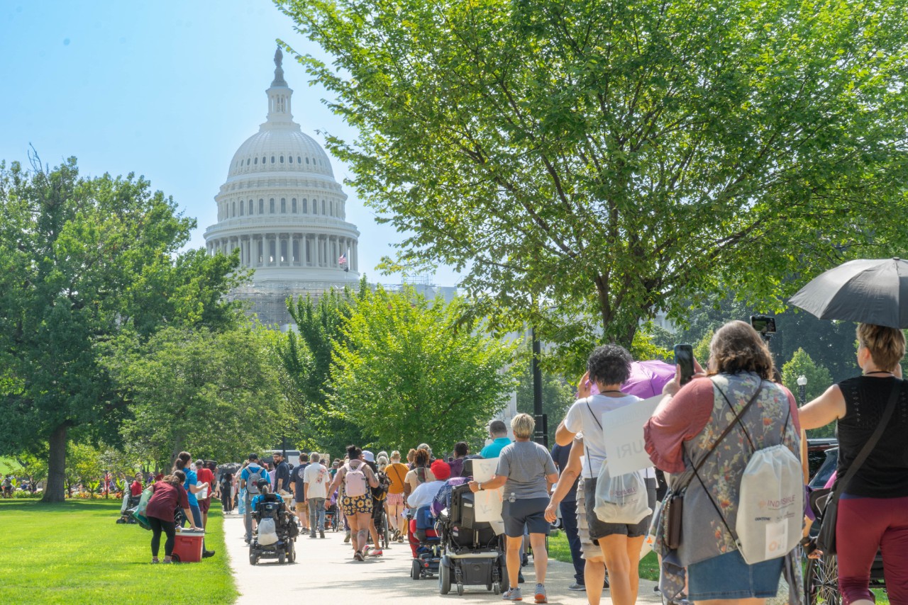 A group of people with and without disabilities march with signs toward the U.S. Capitol building in Washington, D.C. 