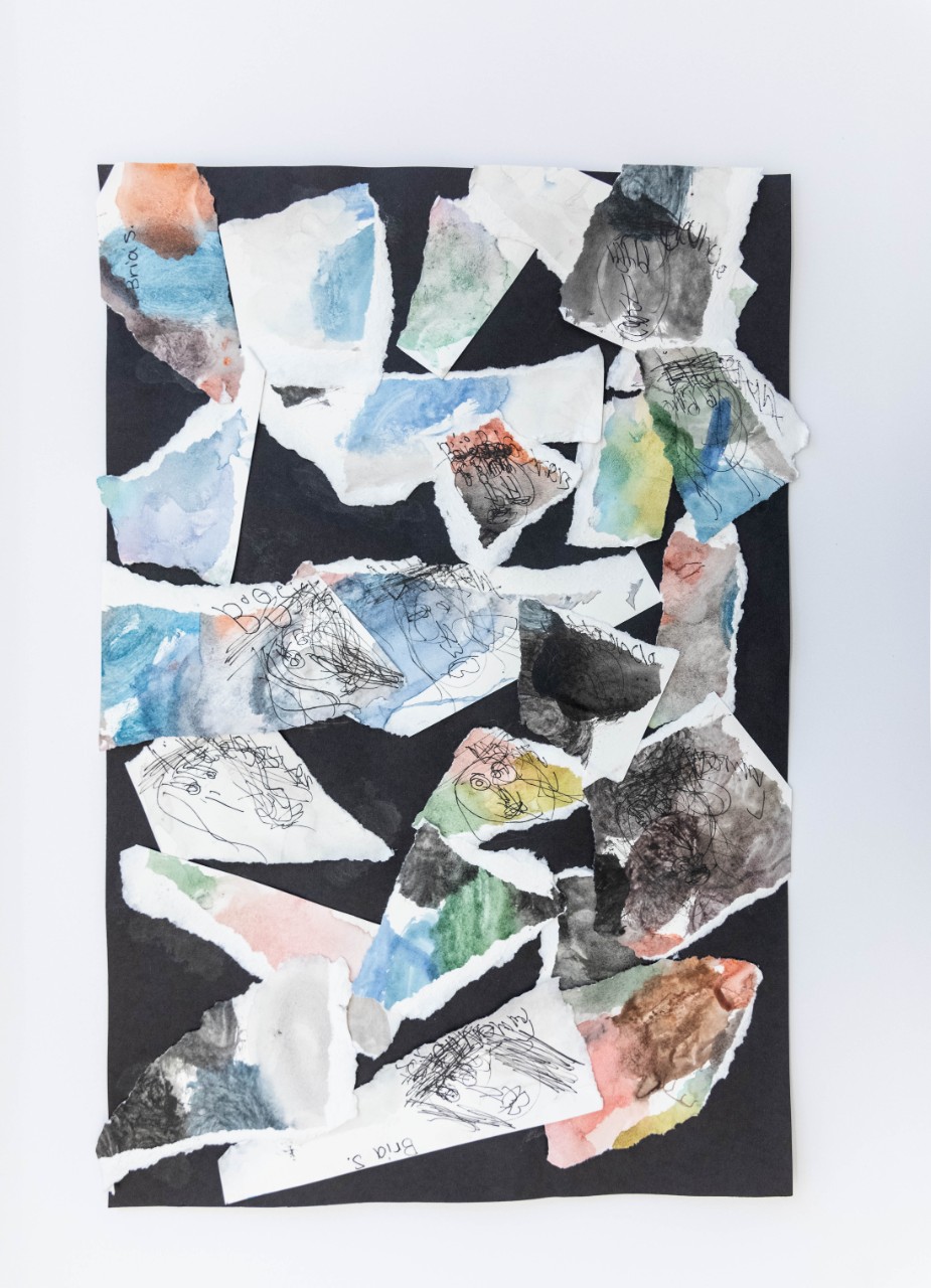 Torn scraps of paper with watercolors pasted onto a black background