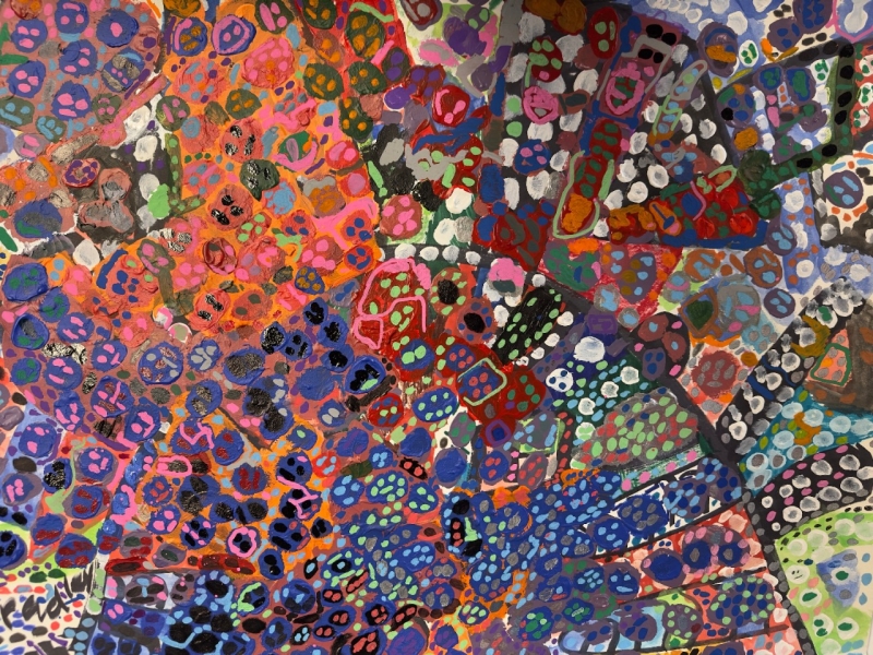 A vibrant abstract painting filled with intricate patterns and colorful shapes. The composition is dominated by clusters of circular and oval forms outlined in bold colors, including blue, red, orange, green, and purple. Some areas have a dense, almost mosaic-like texture, while others are more open, allowing contrasting colors to interact dynamically. The painting has an energetic, layered quality, with a mix of organic and geometric patterns creating a sense of movement and depth.
