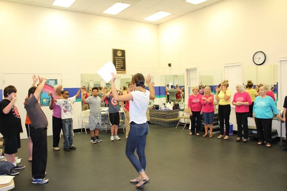 Lili Lyne (TR Intern) instructing a music theory game called High-Middle-Low. a female instructor leading youth participants and volunteers in a game