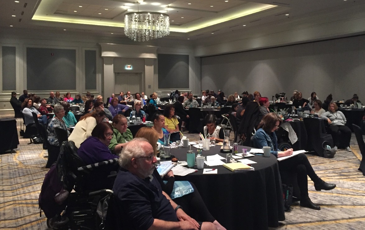 Ned and Reunion crowd listening to speakers large crowd of seated people, adults with and without disabilities, attending the Council's 2018 partners in policymaking reunion