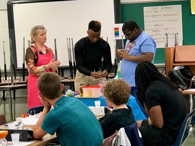 University of Tennessee Ag Extension June Puett teaches Camp Work Readiness participants, Marlon Kennemore and Martin Boatwright, how to prepare a nutritious meal. several people in a classroom standing around a table, working on a food preparation activity