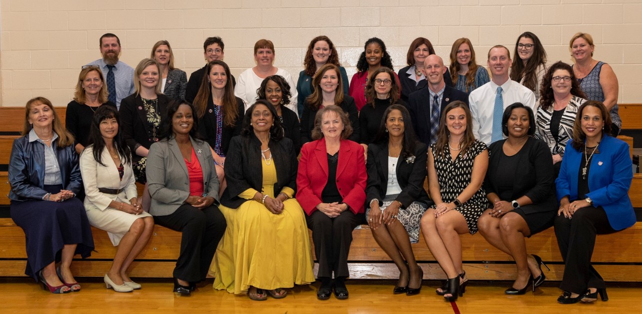 2018 LAEDS graduation group photo of a diverse group of about 30 adults who are state employees, sitting together on gym bleachers