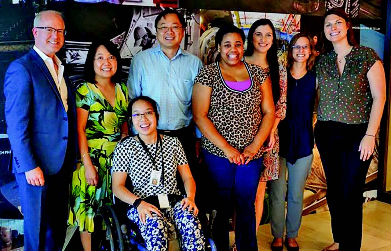 Peach Chinratanalab and Brittenee Whitelow group photo with ECD staff and their families There is a group photo of eight individuals, who are the interns, their family members and job coaches. It is a very ethnically diverse group of two men and six women. One of the young women is in a wheelchair.