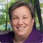 headshot of Alicia Cone, a white woman with short gray hair and an embroidered purple blouse with a state of TN and a leadership academy pin on it