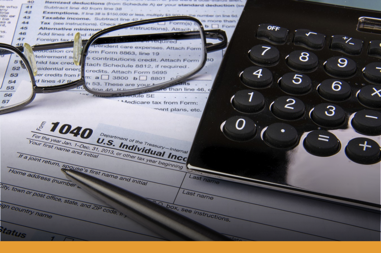 Reading glasses, calculator, pen on top of tax forms