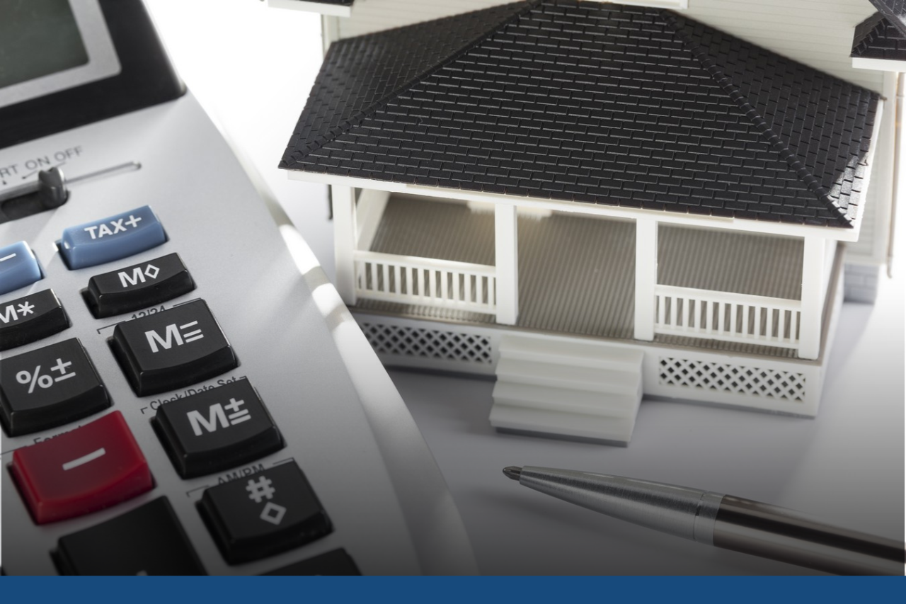 Calculator next to a pen and model of a house