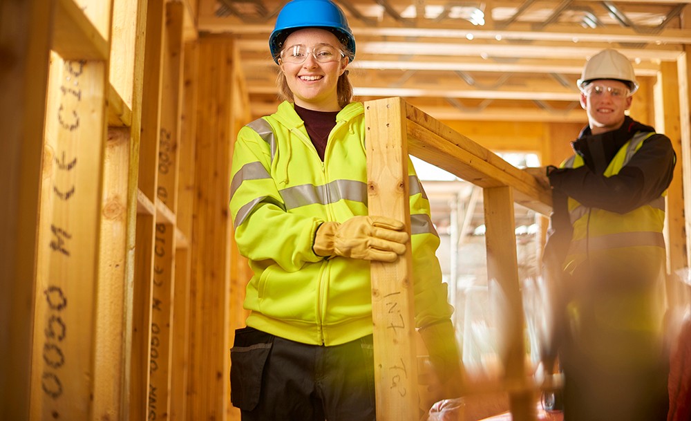 Two young people wearing safety goggles and hats on a construction site