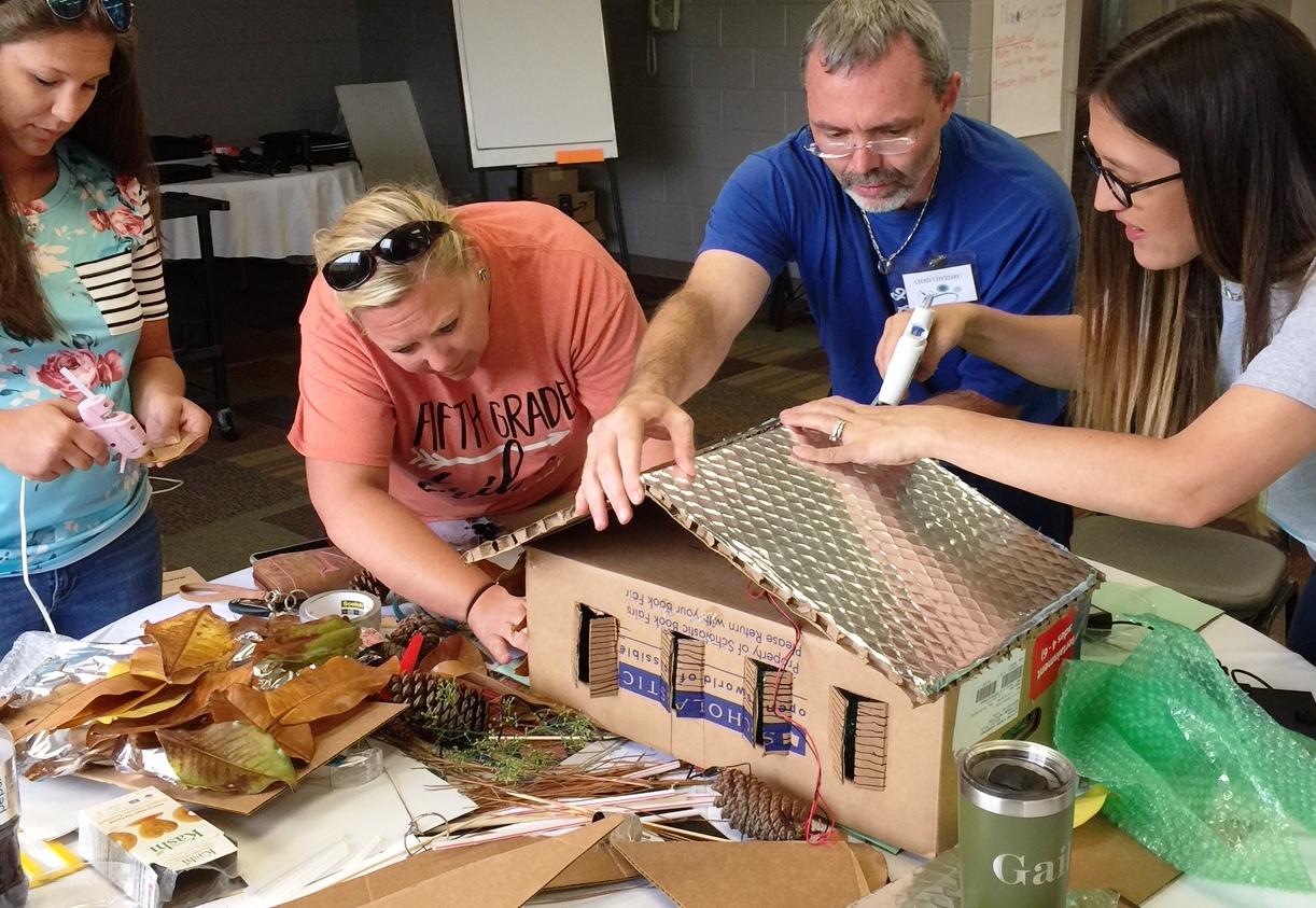 People working on a miniature energy efficient house