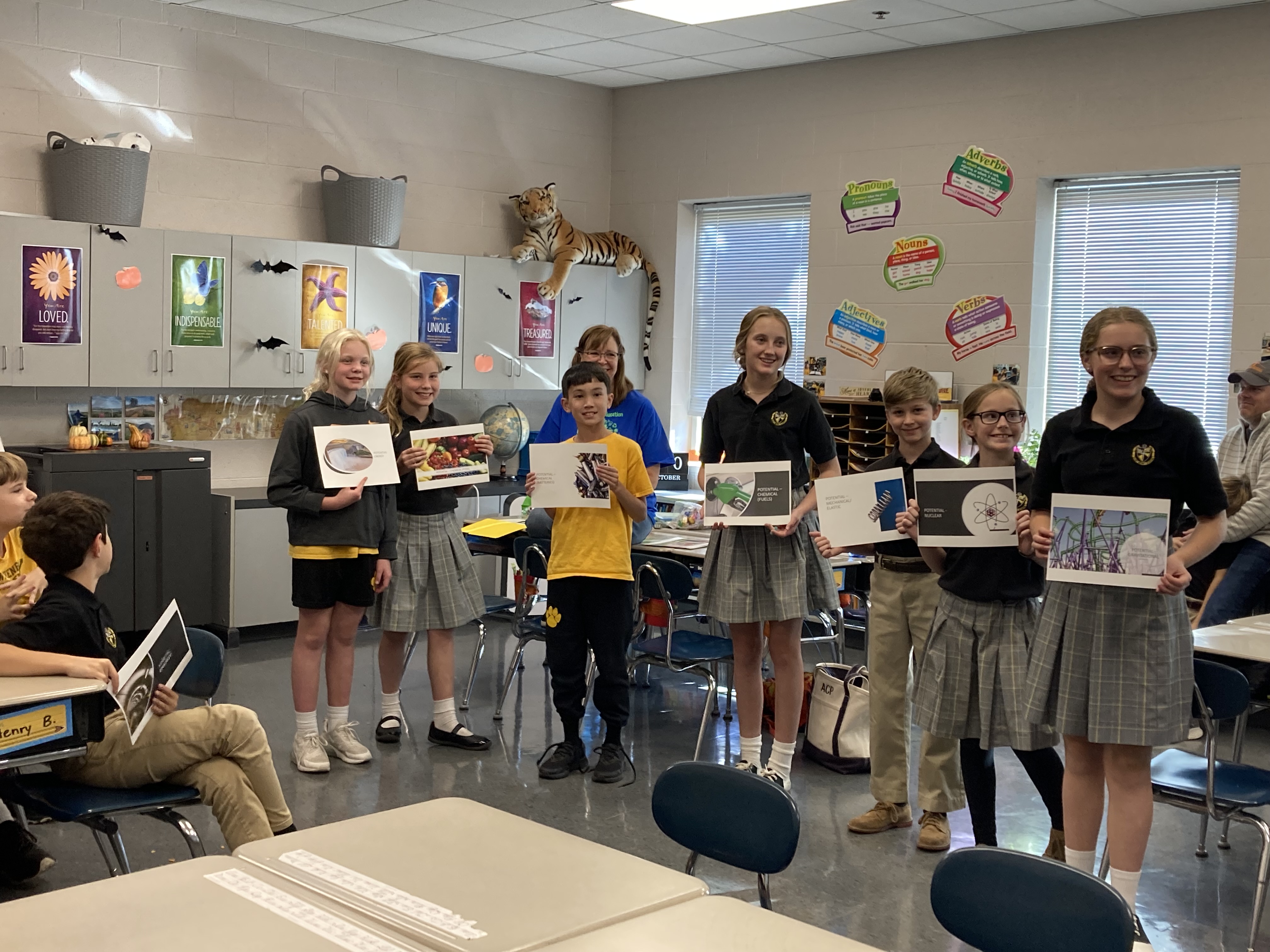 children holding up printed slide show slides during classroom activity