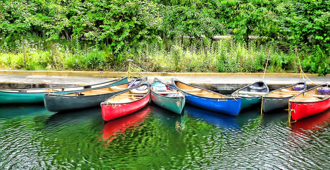 Colorful canoes tied along a dock on calm green water.