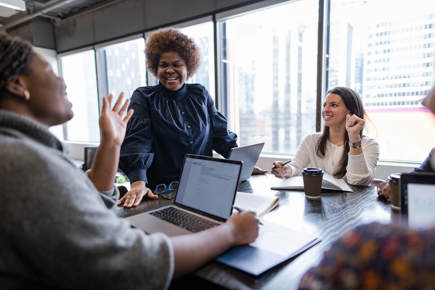 Image of employees sitting at a conference desk speaking to each other.