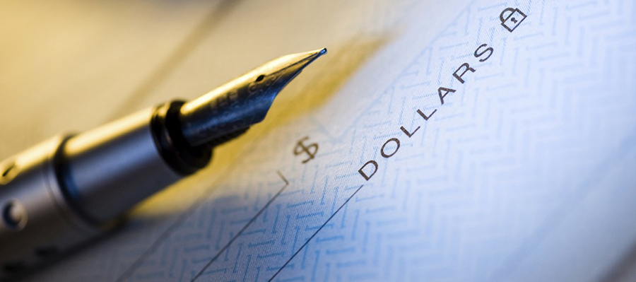 a fountain pen sits atop a blank check signifying opportunities for funding