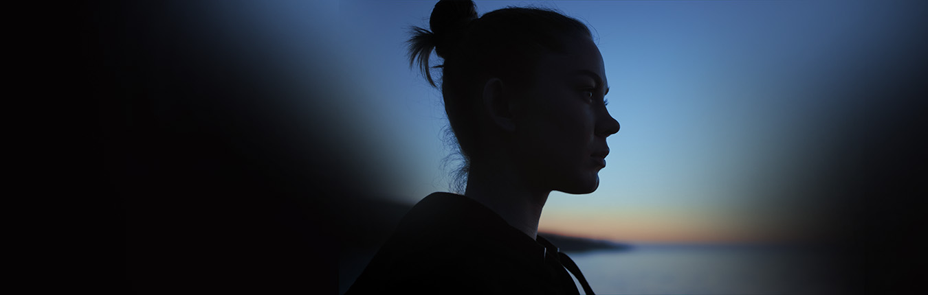 A silhouette of a female in front of a sunset.