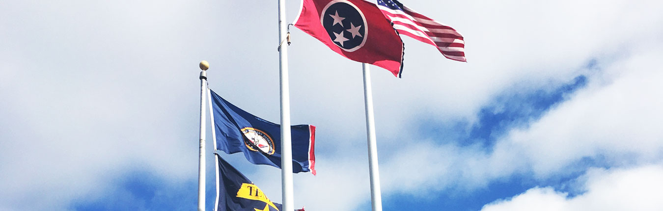 Flags wave in front of Joint Force Headquarters in Nashville, Tenn. Flags shown are the American Flag, State of Tennessee Flag, Tennessee Military Department Flag, and the Tennessee Emergency Management Agency Flag.