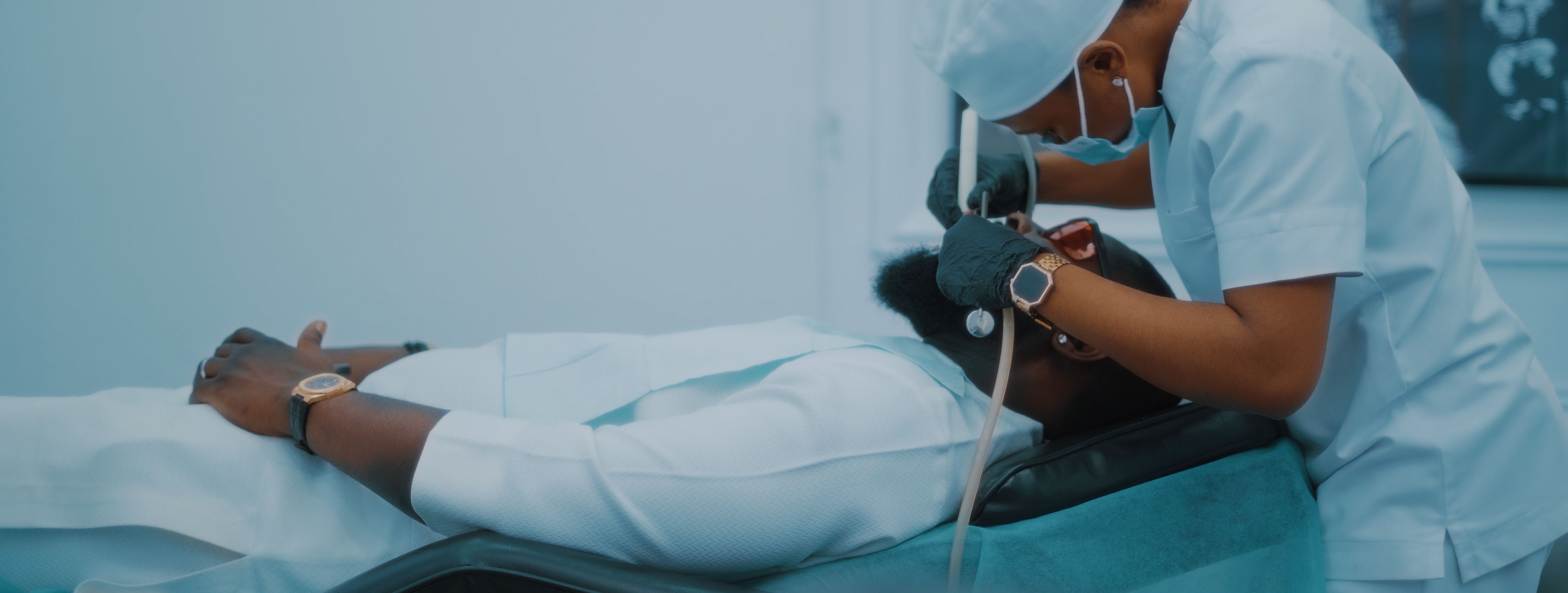 A healthcare professional provides patient care in a clinical setting, using medical equipment while a patient rests on an examination table.