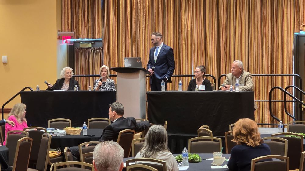 Barrett Frederick moderating a session on Return to Work on stage in a hotel ballroom.