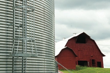 Close up of a grain bin with red barn in background