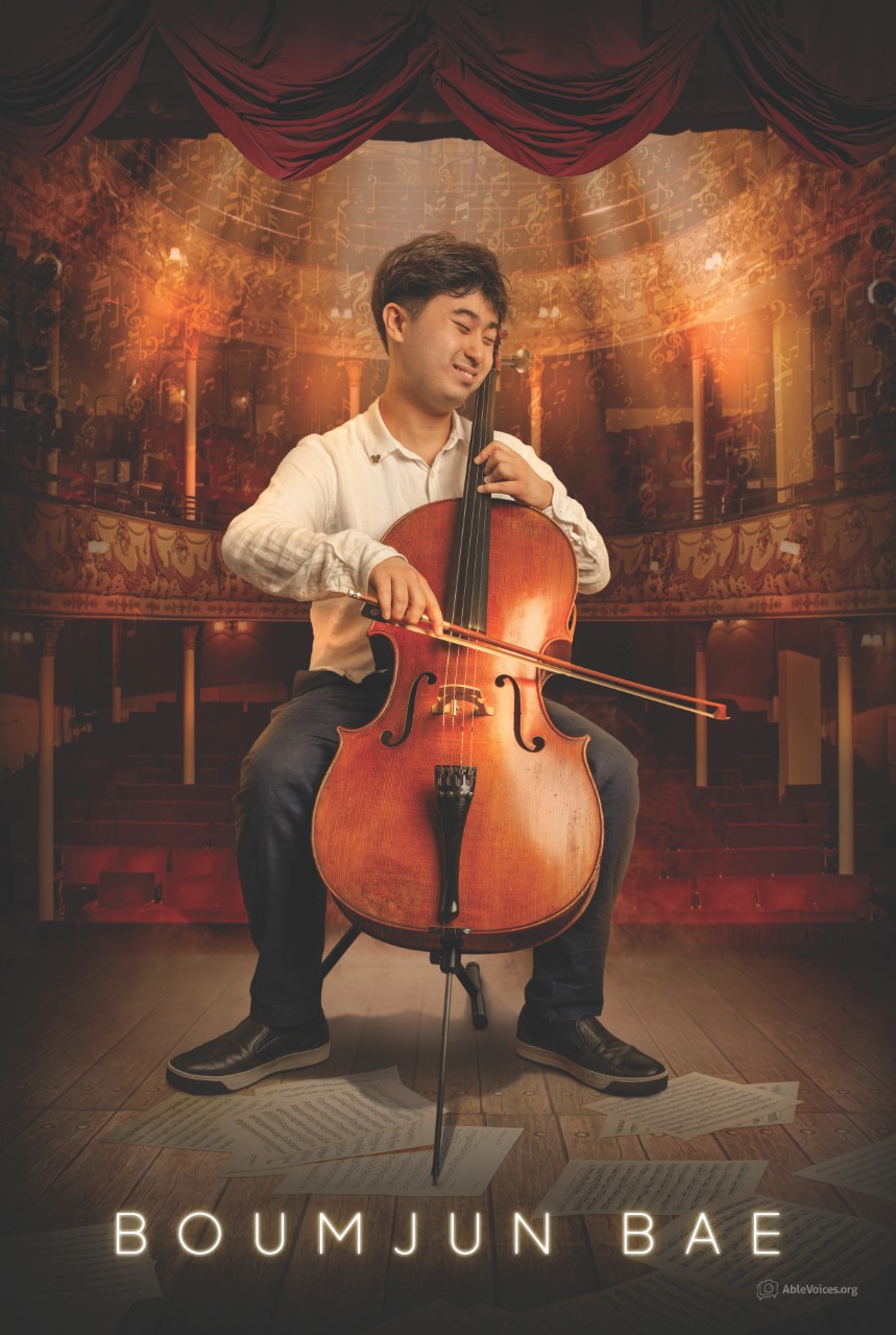 a Young Asian man seated, playing a cello, with a big smile and his eyes closed. He’s pictured on a stage in a beautiful old concert hall with red velvet seats and golden balconies behind him