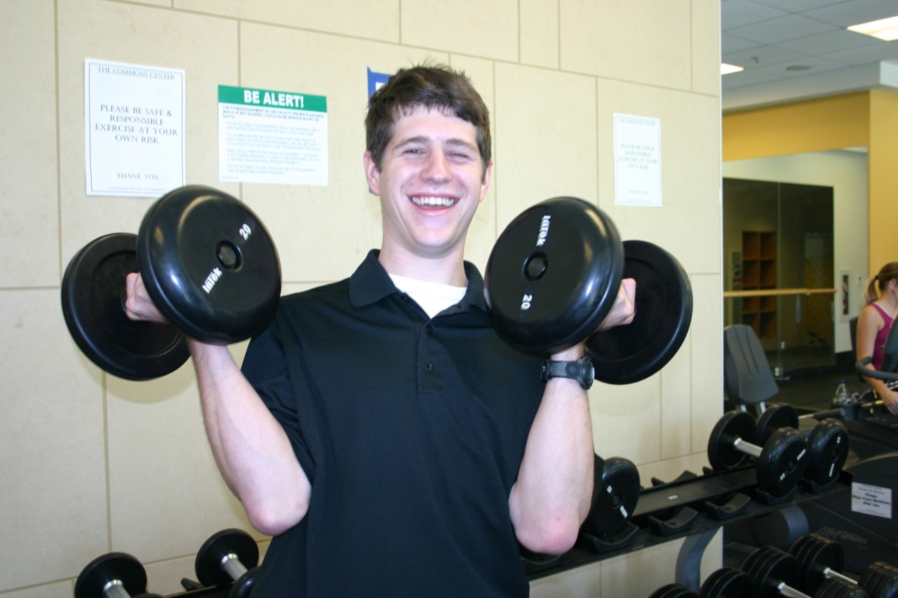 Andrew van Cleave when he was at Next Steps, holding two weights in the gym with a big smile.