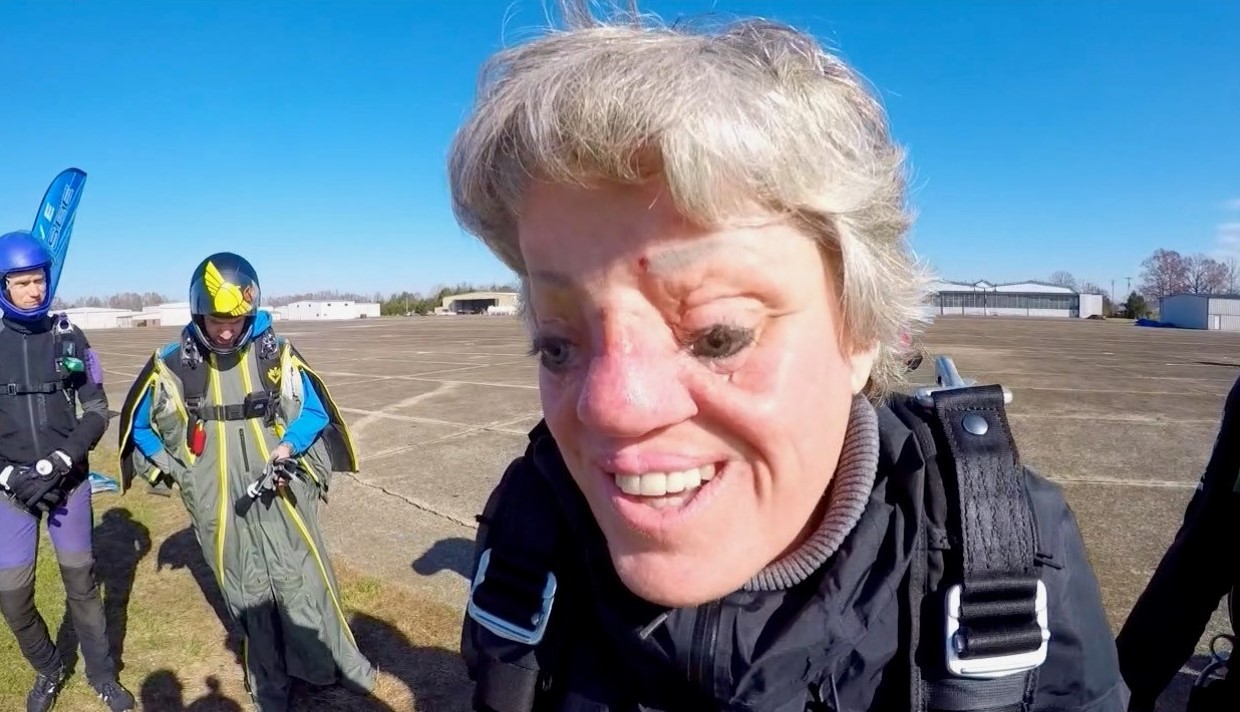 A close-up photo of Sarah’s smiling face after landing safely on the ground standing on an airport tarmac