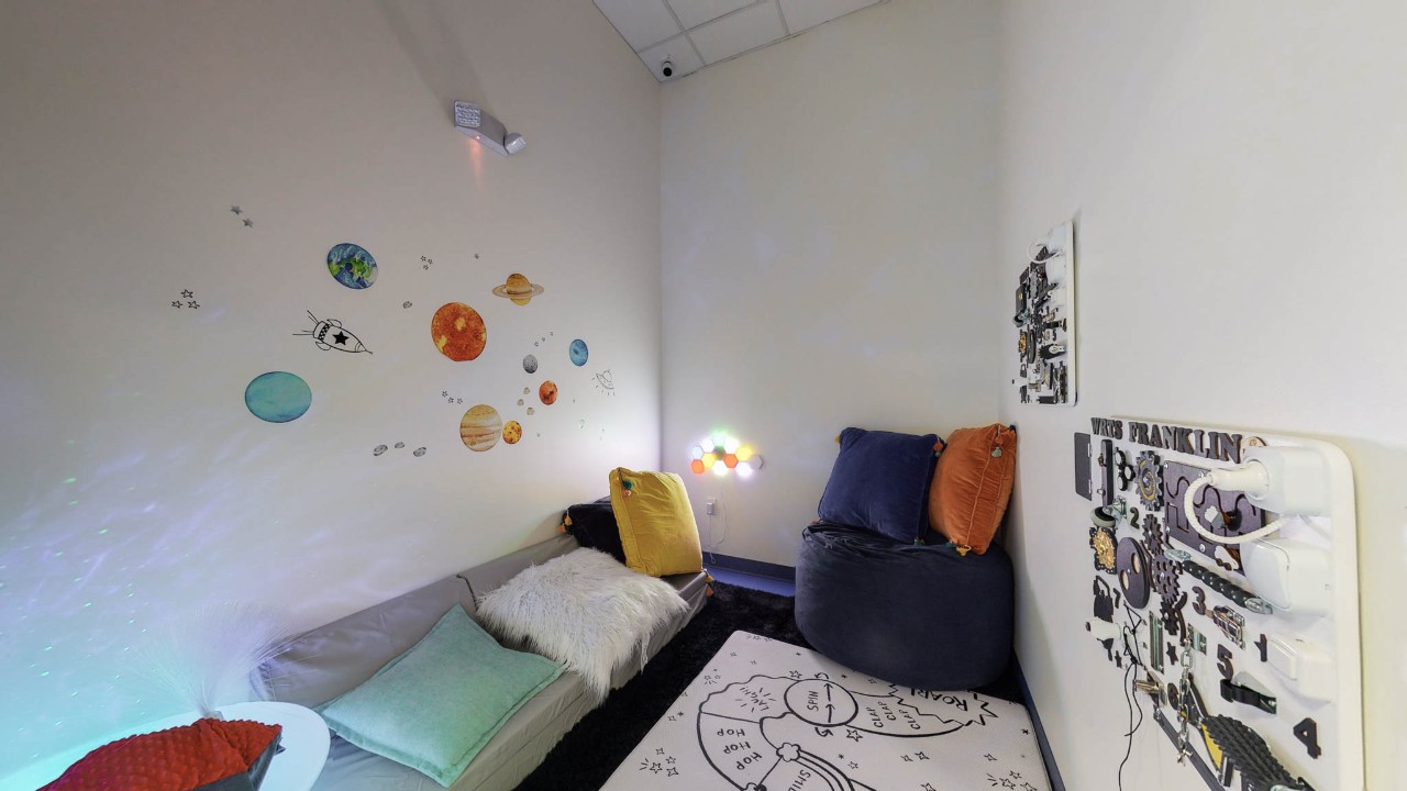 a dimly lit sensory room filled with pillow and fun but calm furnishings