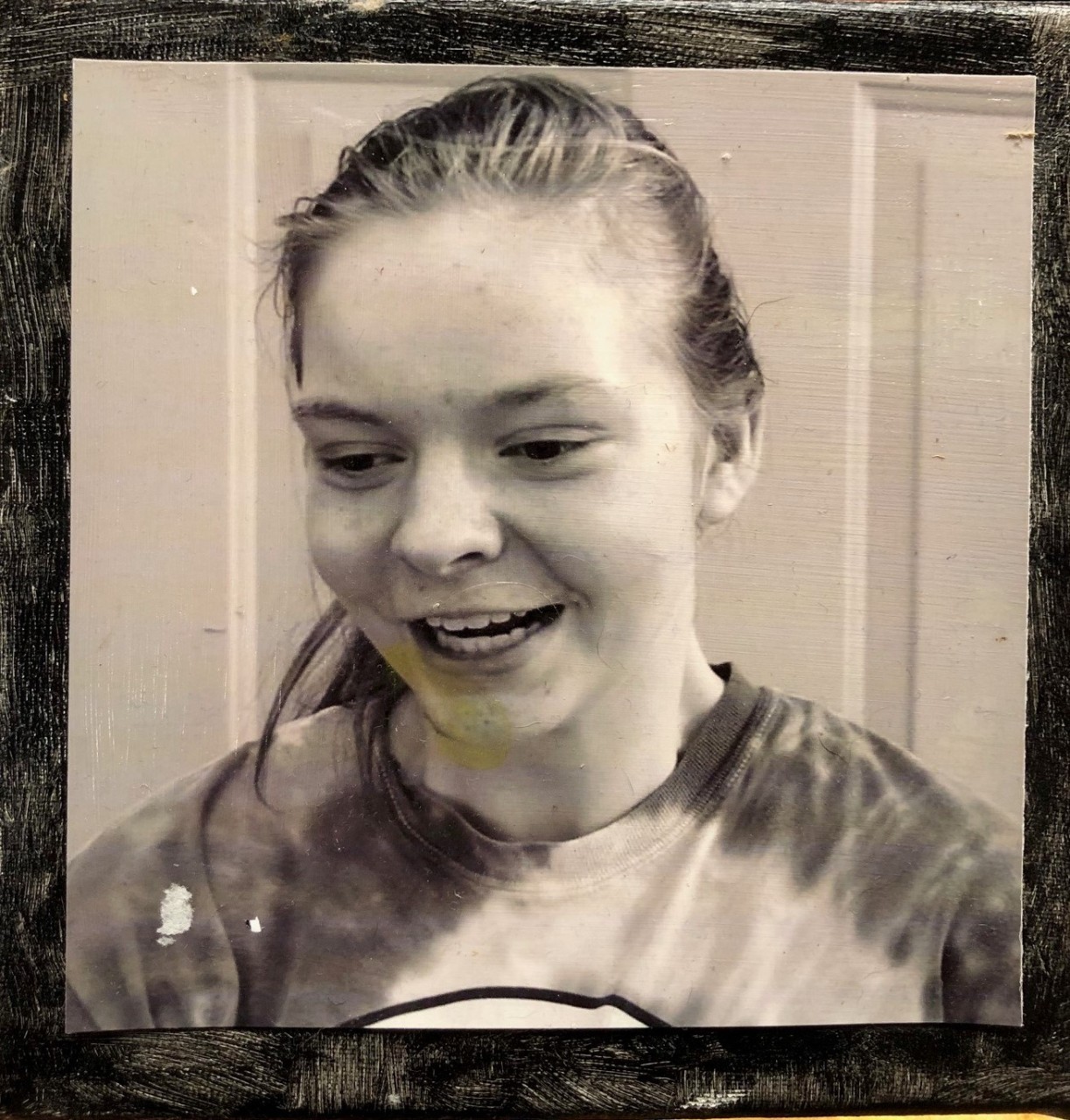 a sepia toned square headshot of Teresa, a young white woman with light hair pulled back in a ponytail, wearing a tie-dyed shirt