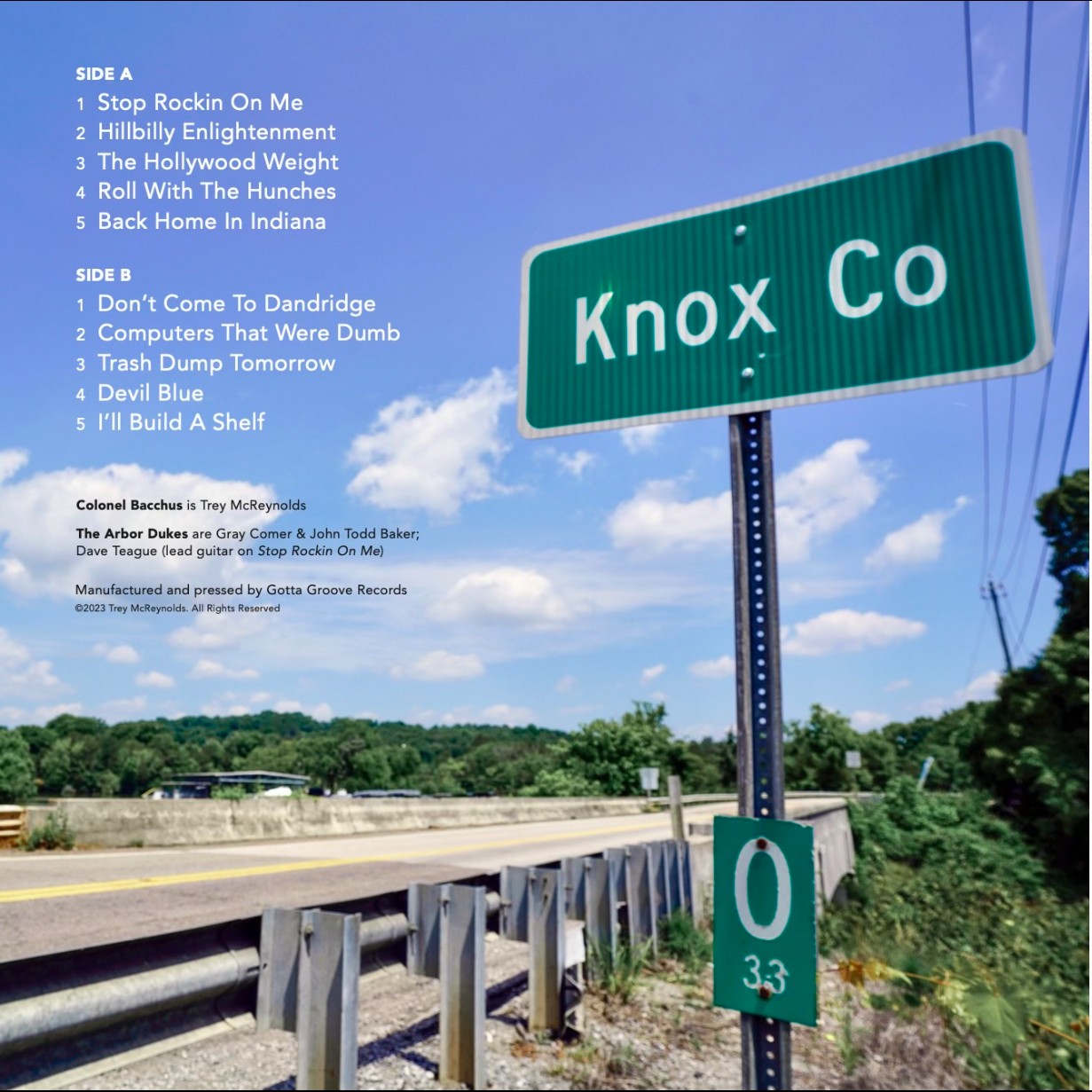 Back album art shows a highway from the outside of a railing, with a street sign reading “Knox Co.” Song list reads: “SIDE A – 1. Stop Rockin On Me 2. Hillbilly Enlightenment 3. The Hollywood Weight 4. Roll With The Hunches 5. Back Home in Indiana. SIDE B – 1. Don’t Come to Dandridge 2. Computers That Were Dumb 3. Trash Dump Tomorrow 4. Devil Blue 5. I’ll Build A Shelf - Colonel Bacchus is Trey McReynolds – The Arbor Dukes are Gray Comer & John Todd Baker; Dave Teague (lead guitar on Stop Rockin On Me) – Manufactured and pressed by Gotta Groove Records ©2023 Trey McReynolds. All Rights Reserved.” 