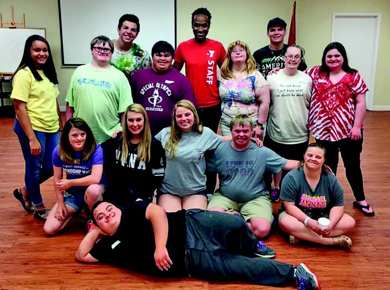 a large group shot of participants and volunteer staff of Camp EmPower, MePower. They are all casually dressed and have big smiles on their faces. Several of the people have their arms around the shoulders of others