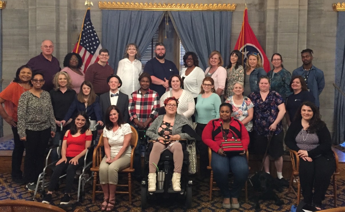 a large group photo of the graduating Partners class at the Old Supreme Court Chambers at the Capitol; the group includes about 30 adults with and without visible and invisible disabilities