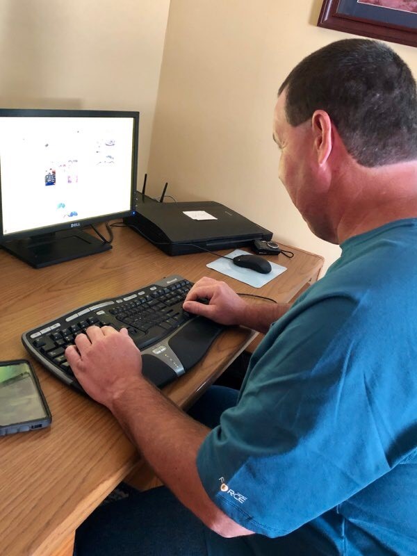 a middle-aged man, Jeff, sitting at a computer, typing on a keyboard. The caption reads: “Jeff uses accessibility software and voice technology to conduct business on his laptop.” 