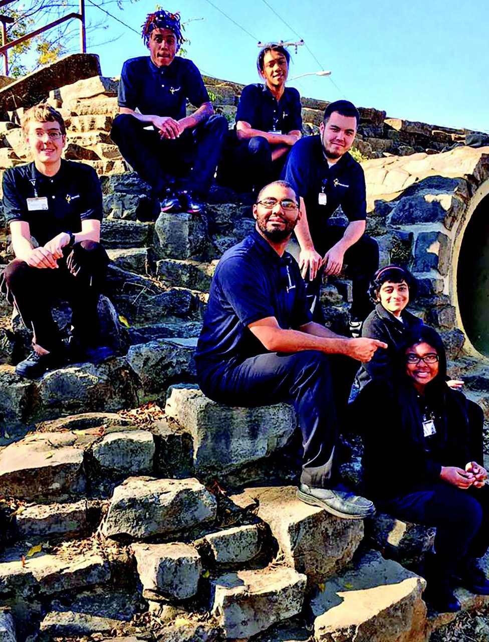 Project SEARCH Vanderbilt Intern Class 2017. This is a diverse group of young people, all in dark blue uniforms. They are posing on a curved stone wall.