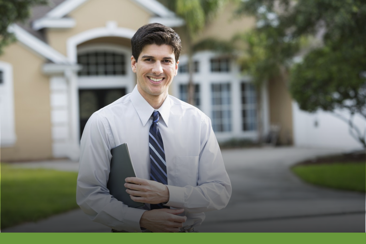 Smiling formally dressed man holding a folder while standing in front of a house