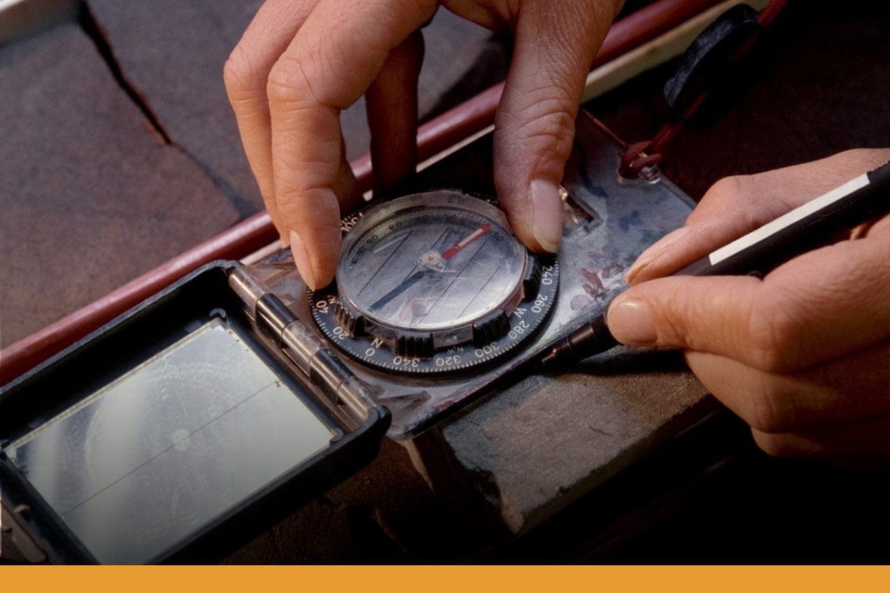 Pair of hands using a geologists compass