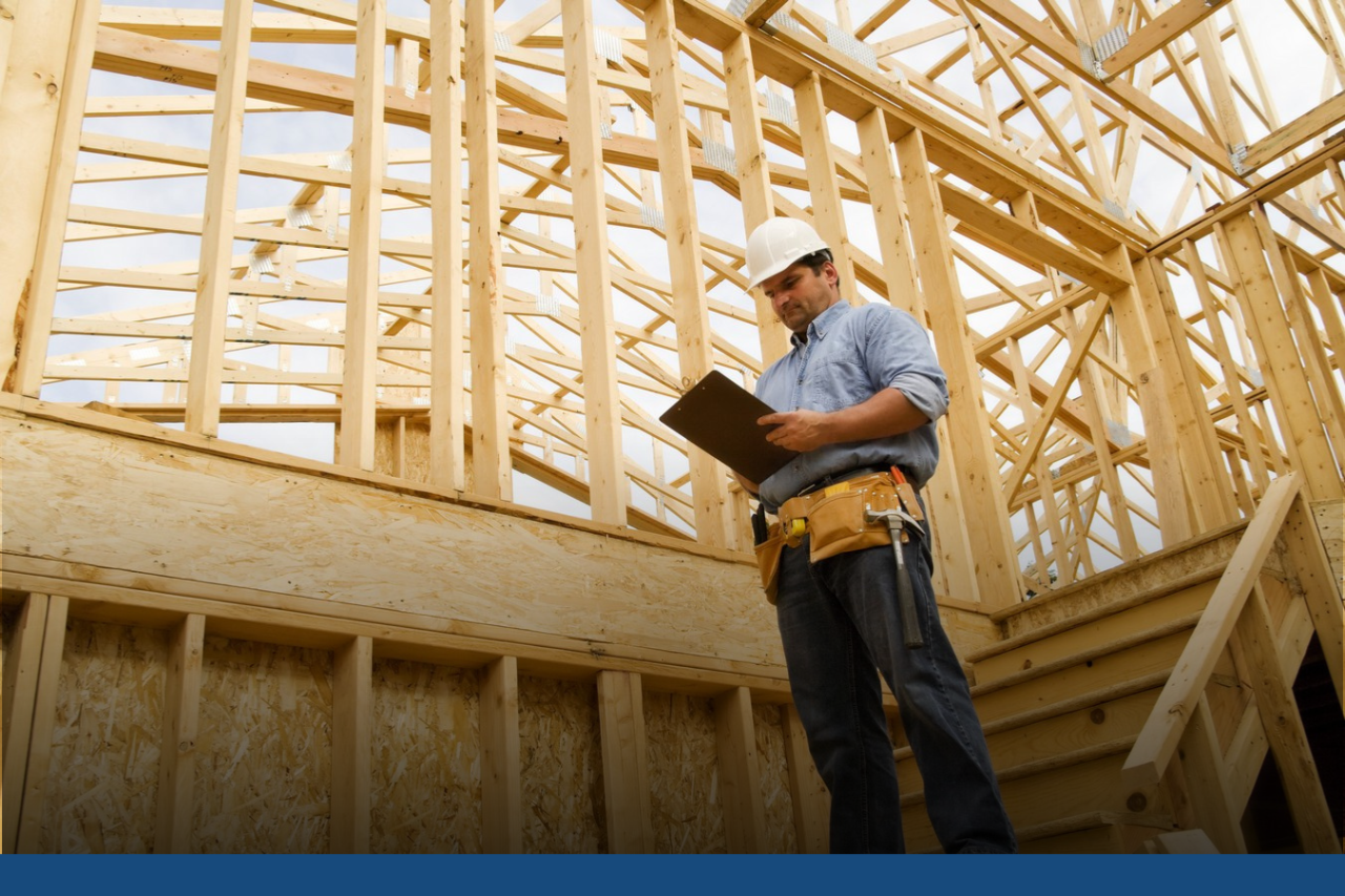 Man wearing a hard had with clip board at a house under construction