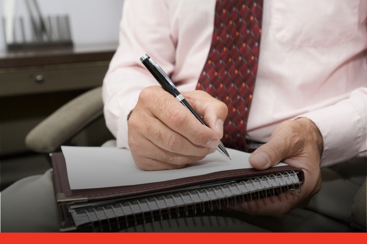 Hands of a formally dressed man writing on a notepad