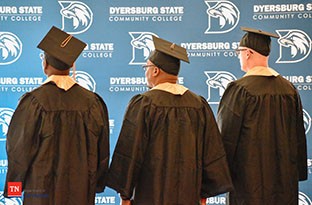 Photo of back of three people in graduation attire.