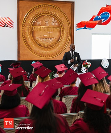 Photo of Graduation Ceremony With Offenders Seated Wearing Caps and Gowns