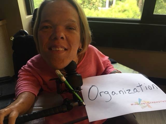 woman in a power chair holding a sign that says organization