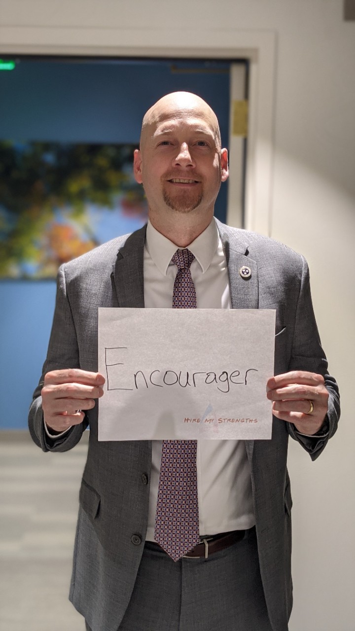 DIDD Commissioner Brad Turner holding a sign that says "Encourager"