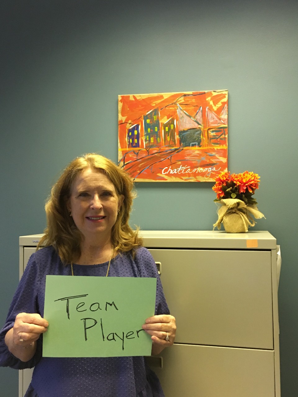 woman holding a sign that says "team player"