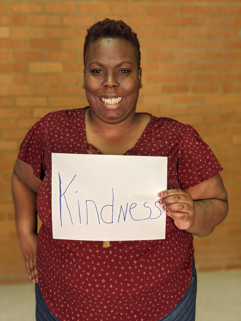 Woman holding a sign that says Kindness