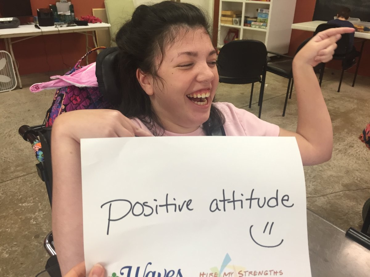 woman in a wheelchair holding a sign that says "positive attitude: