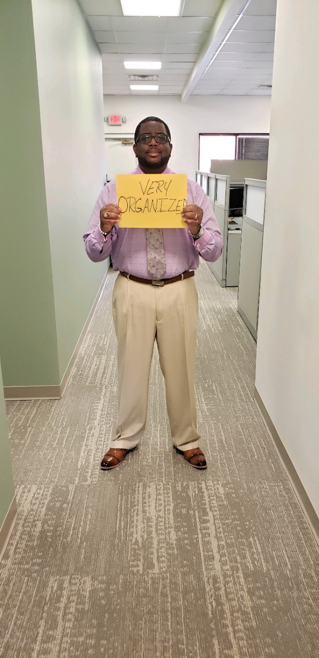 man standing in a hallway holding a yellow sign